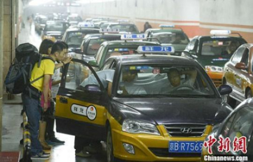 資料圖:市民在北京西客站出租車候車點準備乘車。中新社發 侯宇 攝