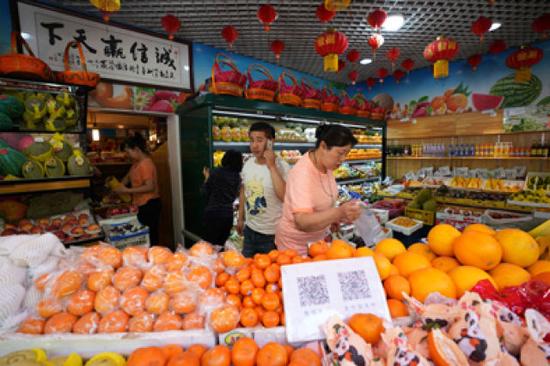 5月8日,店主王繼高(前左)在三源里市場精品水果廳內接聽客戶電話。